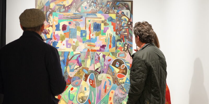 Besucher vor einer bunt gestalteten Arbeit von F. Hufnagel