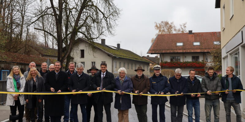 Ein gemeinsamer Schnitt zur offiziellen Freigabe der Brücke: (Personen mit Schere von links) Pfarrer Michel Seifert, Andreas Maierhofer (2. Bürgermeister Gemeinde Polling), Landrat Max Heimerl, stv. Landrätin Ilse Preisinger-Sontag, Bürgermeistersprecher Thomas Einwang, Karl-Heinz Stocker von der Polizei Mühldorf, Peter Weber (IGL, PUTZ + PARTNER mbB Beratende Ingenieure), Robert Martinez (Tiefbauleiter Landratsamt Mühldorf a. Inn), Martin Gebler (Ingenieurbüro Behringer & Partner mbB), Martin Höpp (Fa. Hagn Umwelttechnik GmbH).